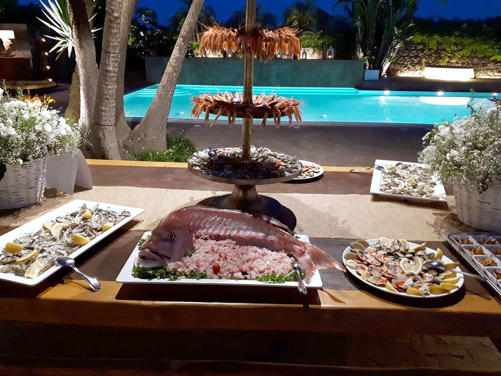 Il buffet di mare a bordo piscina, di sera, con un pesce intero e la tartare