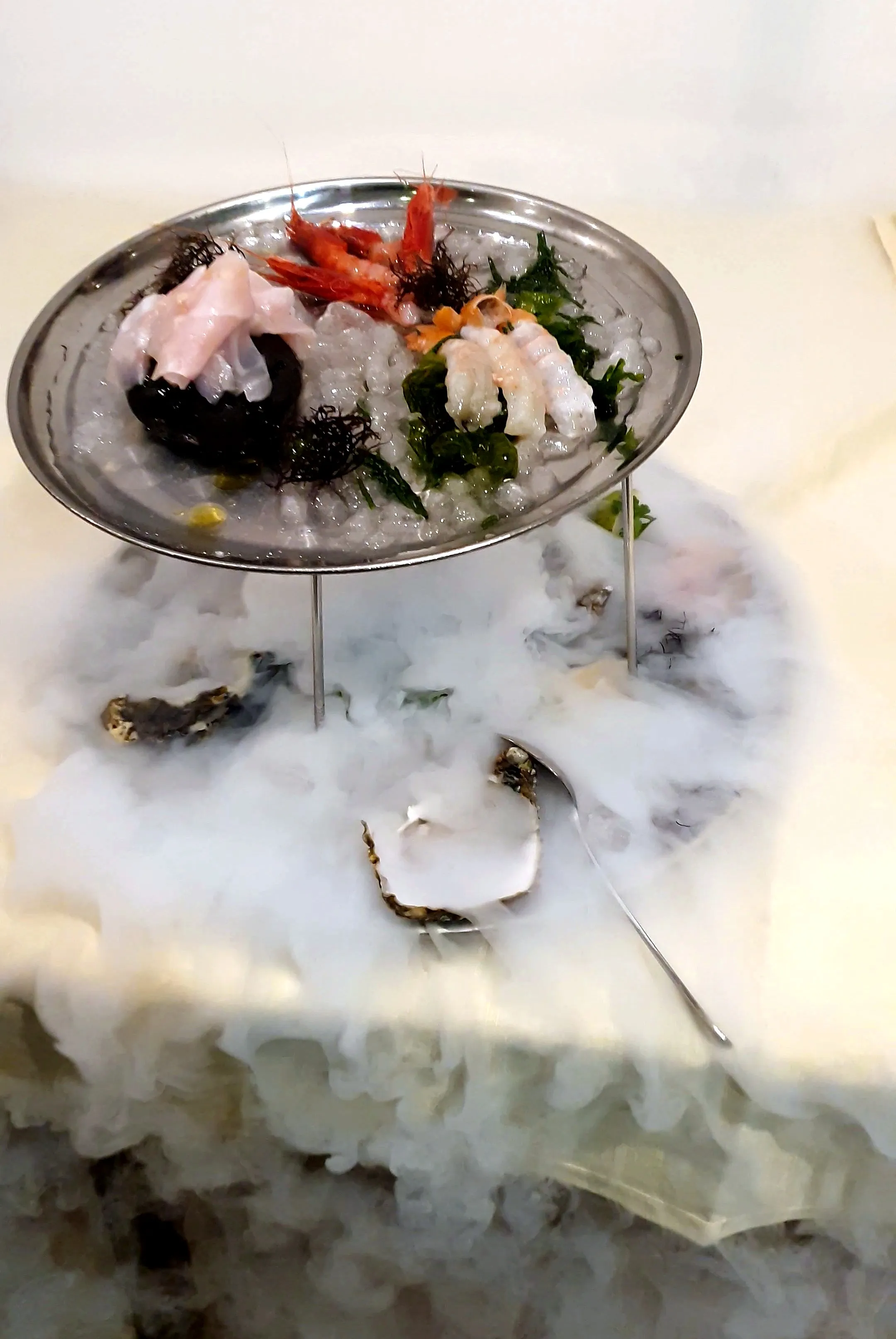 Crudo di mare su un'alzata d'argento, avvolto dal fumo del ghiaccio secco