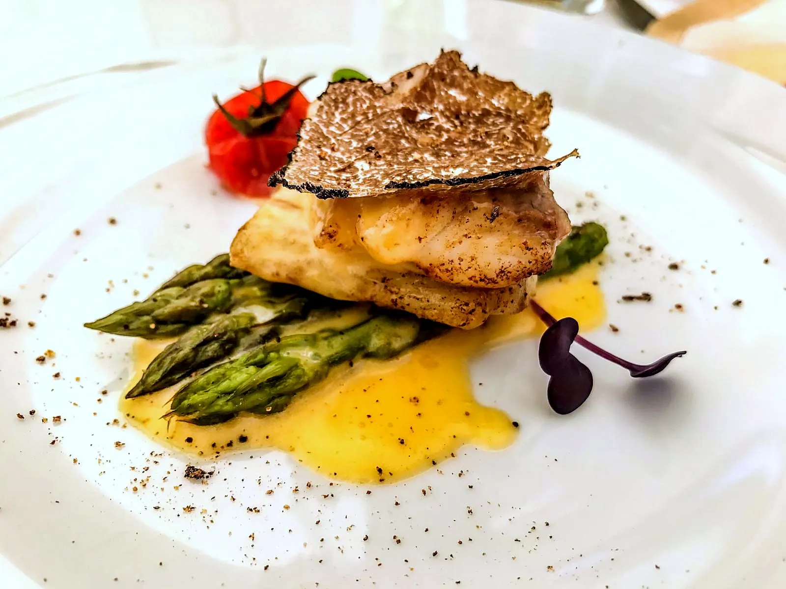 Un filetto di pesce con asparagi, salsa e una lamella di tartufo