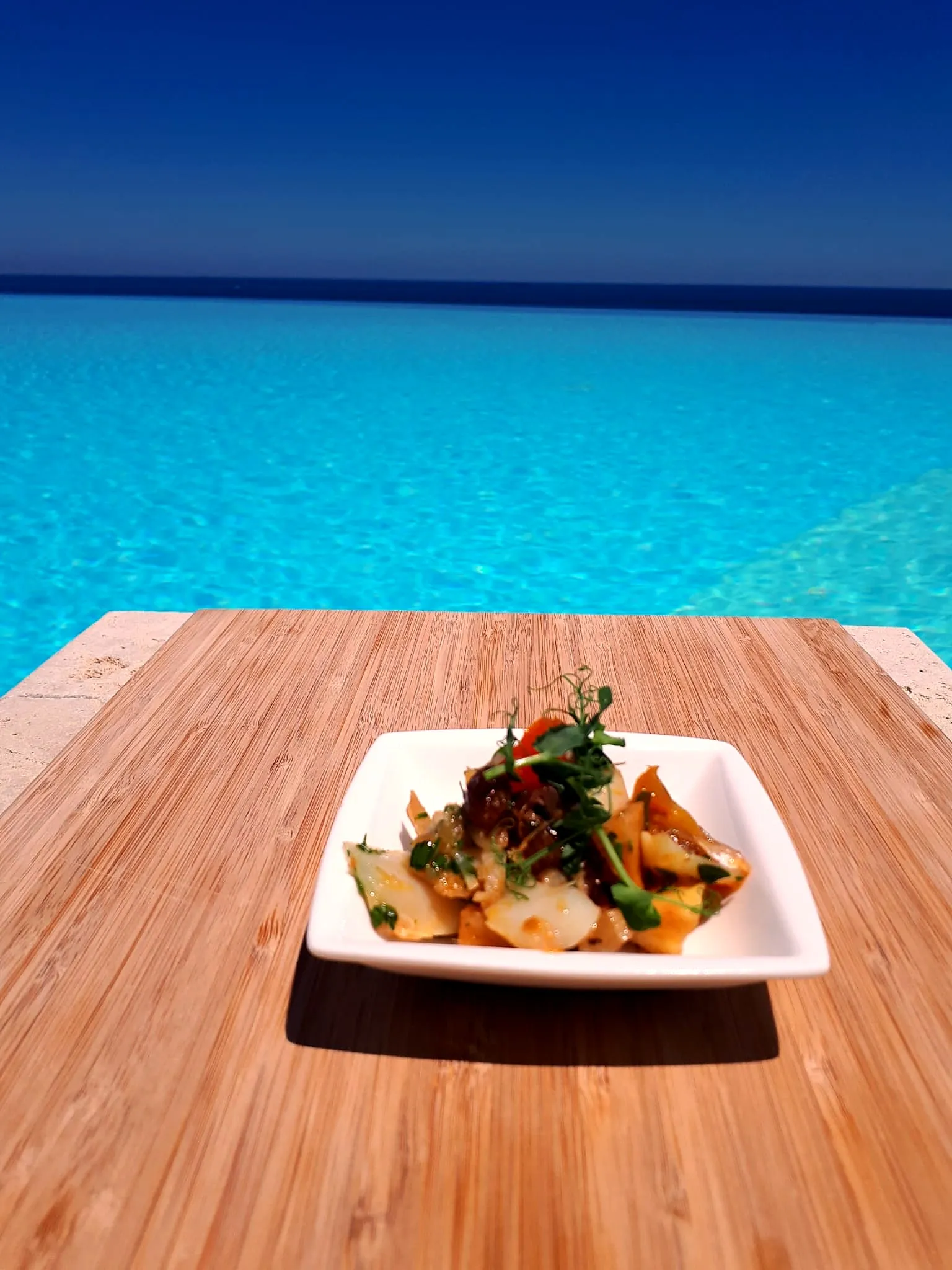 Un piatto di verdure e germogli su un tagliere, con il mare sullo sfondo
